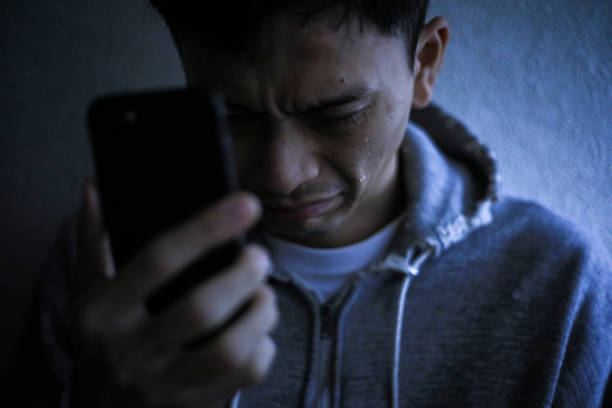  A man holding a smartphone and shedding tears